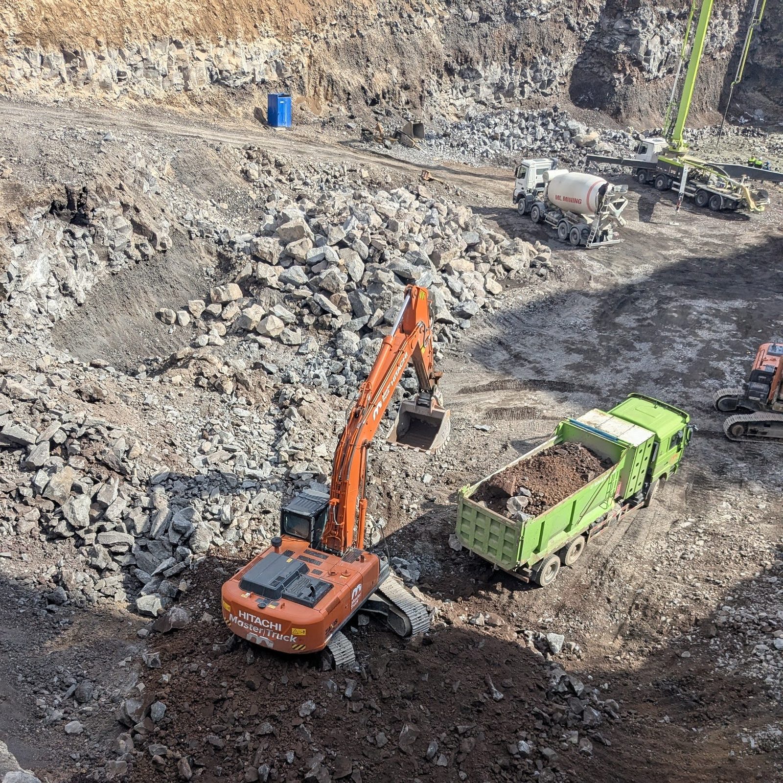 Master Truck-ի Hitachi էքսկավատորը ինքնաթափ է բեռնում ժայռային գրունտով հիմնափոսում